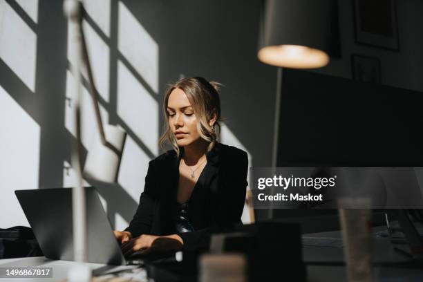 young businesswoman working on laptop sitting at office - woman shadow stock pictures, royalty-free photos & images