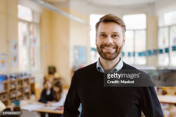 portrait of smiling male teacher with stubble in classroom - male teacher in a classroom stock-fotos und bilder