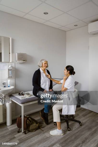doctor consulting senior patient siting on bed in clinic - doctor stethoscope patient whole body stock pictures, royalty-free photos & images