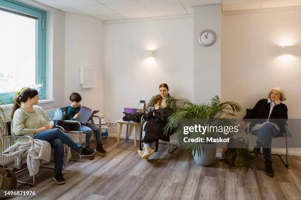 patients sitting on chair while waiting in clinic - wartezimmer stock-fotos und bilder
