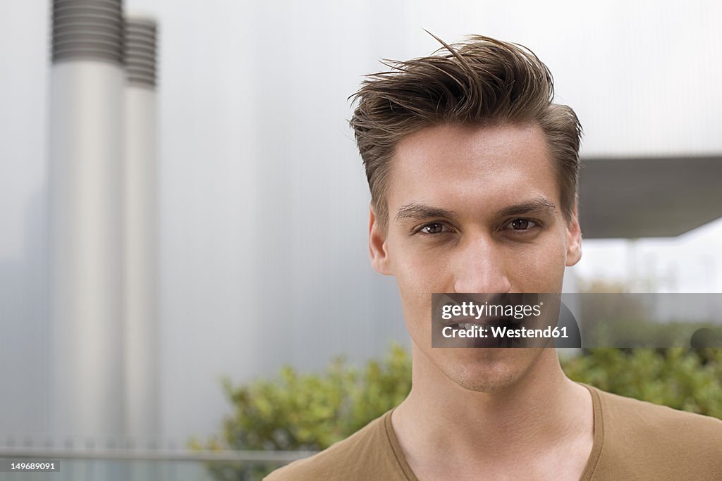 Germany, North Rhine Westphalia, Duesseldorf, Young man in front of building, portrait