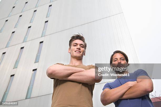 germany, north rhine westphalia, duesseldorf, two trainees standing in front of building, smiling, portrait - omlaag kijken stockfoto's en -beelden