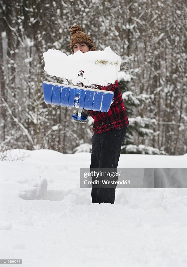 Austria, Young man shoveling snow, portrait