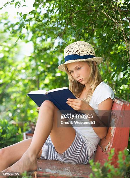 austria, teenage girl reading book in garden - teenage girls barefoot stock-fotos und bilder