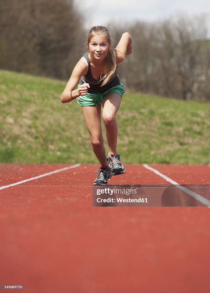 Austria, Teenage girl running on track, portrait