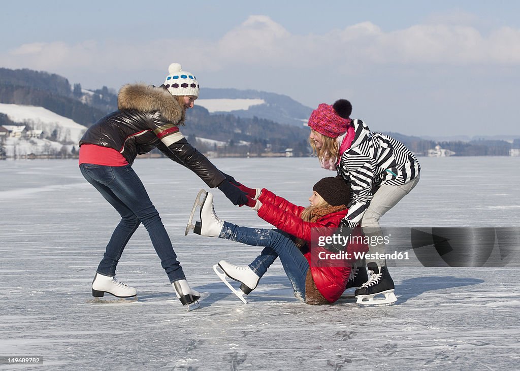 Austria, Teenage girl fallen on ice rink and friends helping her