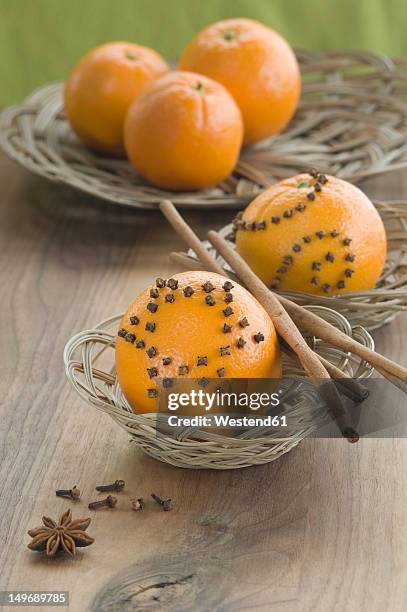 orange studded with cloves and cinnamon stick in basket besides star anise on table - clove stock pictures, royalty-free photos & images