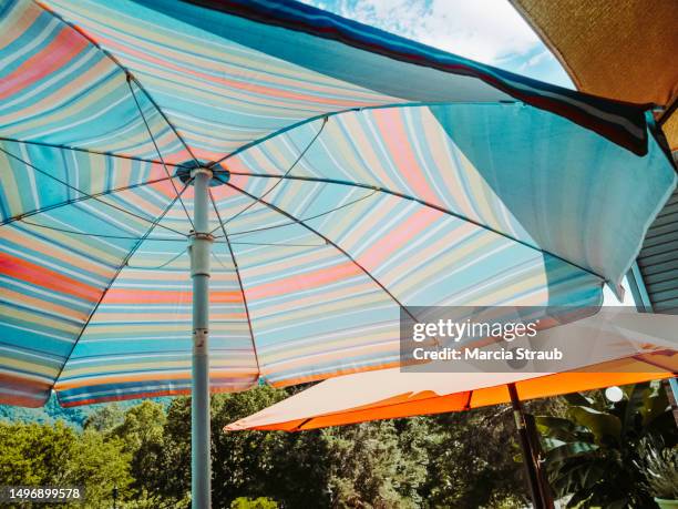 orange and teal patio umbrellas - patio umbrella stock pictures, royalty-free photos & images