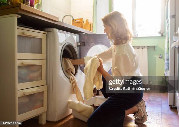 woman putting cashmere sweaters in the washing machine - tvättmaskin bildbanksfoton och bilder