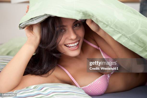 germany, bavaria, young woman on bed, smiling, portrait - verführerische frau stock-fotos und bilder