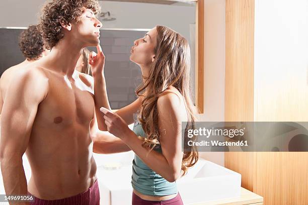 germany, bavaria, young woman applying cream on man face in bathroom - bad relationship stock-fotos und bilder