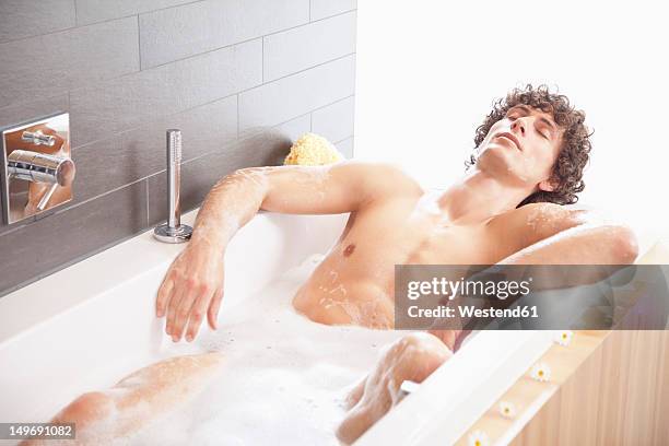 germany, bavaria, young man having bath in bathtub - homem banho imagens e fotografias de stock