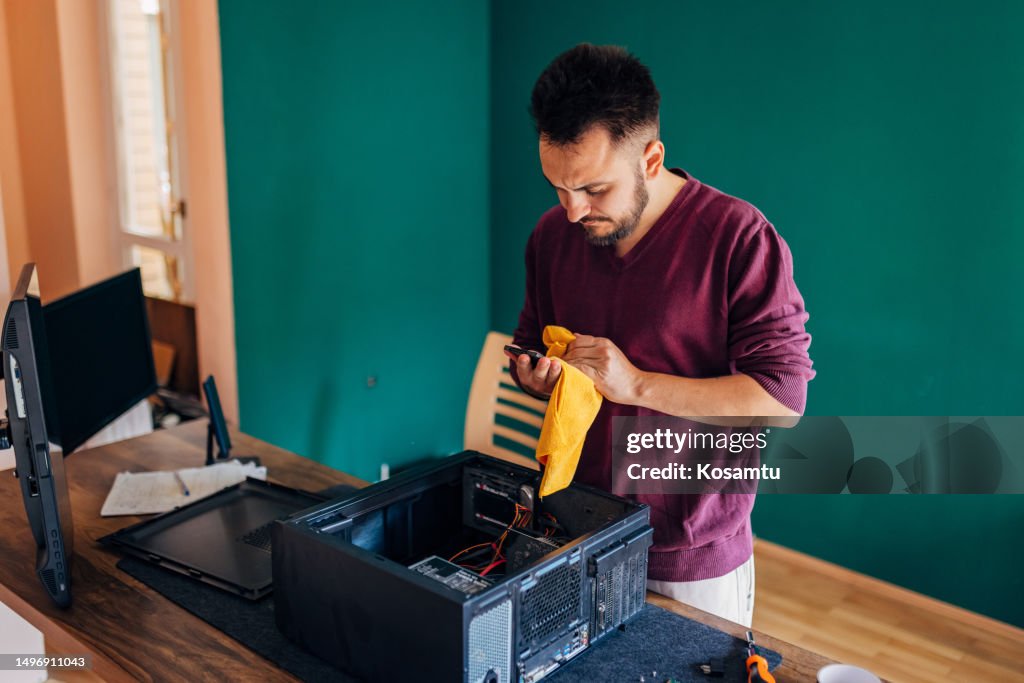 A man uses a rag to clean the SSD part of the computer
