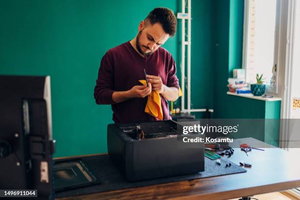 a focused millennial man uses a cloth to clean the ssd part of the computer - spatholobus suberectus dunn stock pictures, royalty-free photos & images