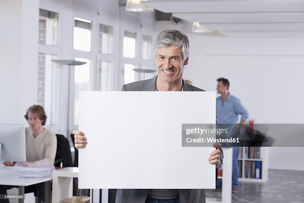 Germany, Bavaria, Munich, Mature man holding placard in office