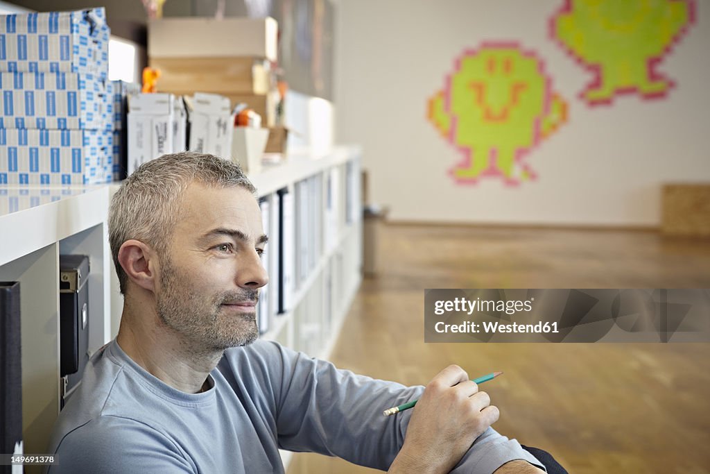 Germany, Cologne, Mature man sitting on floor
