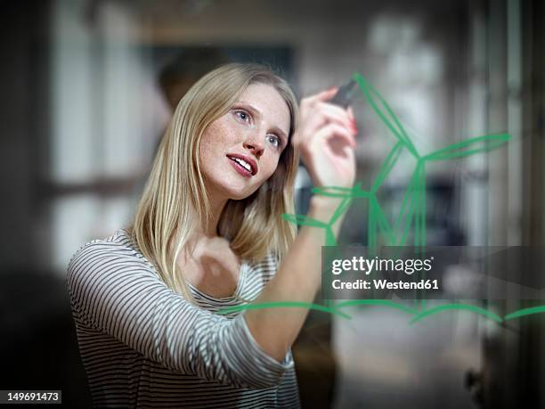 germany, cologne, young woman drawing wind turbine on glass - sustainable economy stock pictures, royalty-free photos & images