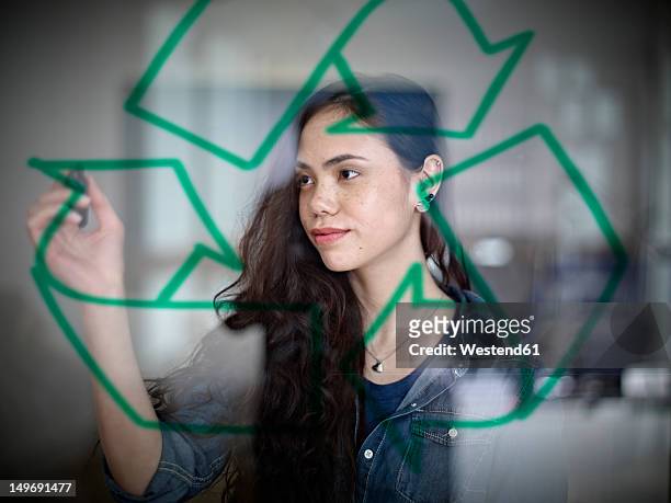 germany, cologne, young woman drawing recycling symbol on glass - responsibility stock-fotos und bilder