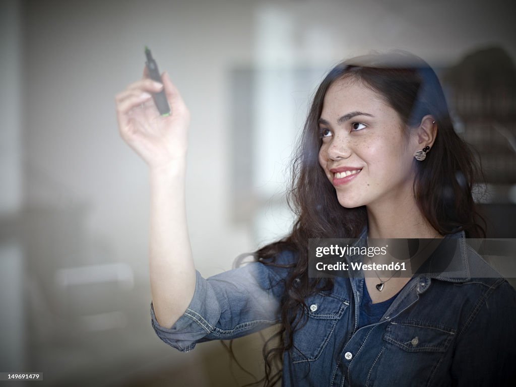 Germany, Cologne, Young woman drawing on glass