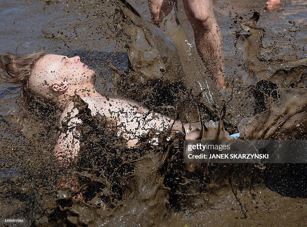 Festival goers jump into muddy water dur