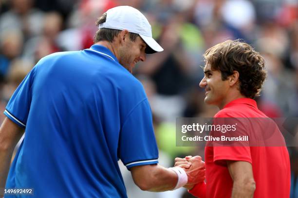 Roger Federer of Switzerland shakes hands with John Isner of the United States after defeating him in the Quarterfinal of Men's Singles Tennis on Day...