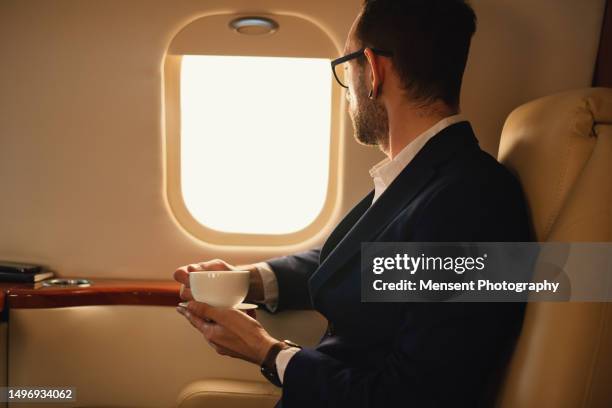 elegant businessman traveler drinks coffee in the first-class private airplane jet - first class stock pictures, royalty-free photos & images