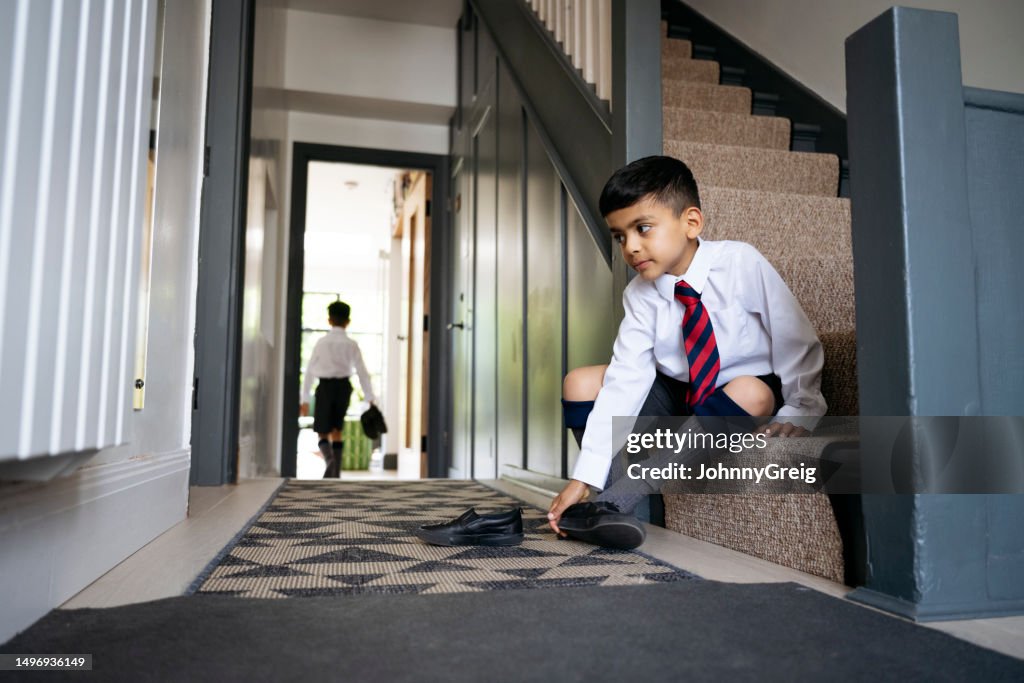 Young British Indian brothers dressing for school