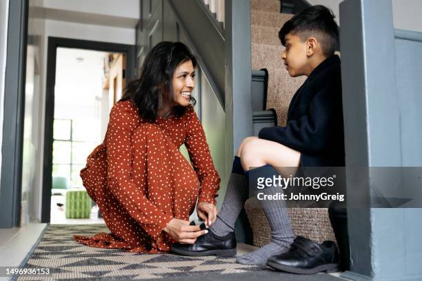 british indian mother helping schoolboy get dressed - women in long dress stock pictures, royalty-free photos & images