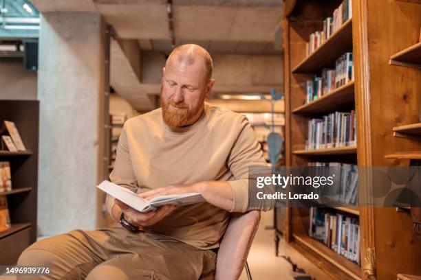 portrait of an adult reader in a library - student reading book stockfoto's en -beelden