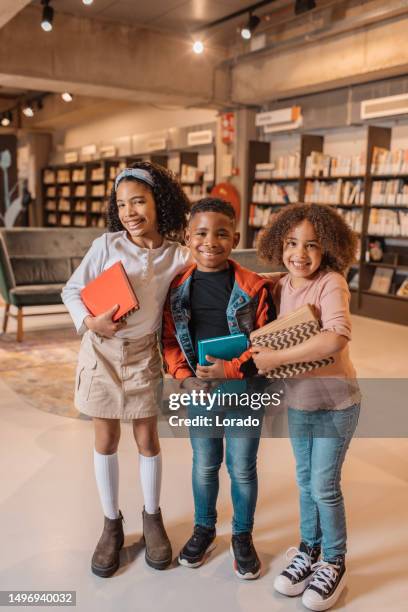 three young black readers in a library - library kids stock pictures, royalty-free photos & images