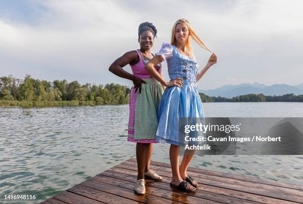 teenage friends standing on pier over lake, bavaria, germany - dirndl stock pictures, royalty-free photos & images
