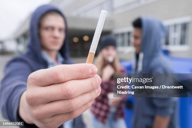 university student showing cigarette in campus, bavaria, germany - boys smoking cigarettes stock pictures, royalty-free photos & images