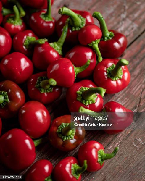 red hot cherry pepper. lot of ripe peppers on wooden surface. pepper harvest. bright spices. spicy food. north american pepper. wooden background. close-up. soft focus. top view - pimientos stock-fotos und bilder