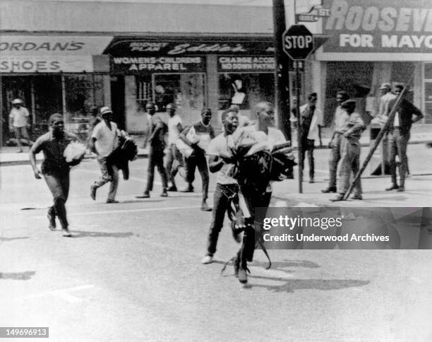 Riots in the Watts section with Negro youths carrying armloads of clothes running from looted stores, Los Angeles, California, August 1965.