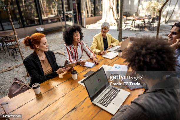 kollegen, die sich während einer besprechung im außenbüro unterhalten - african creative with laptop working outside stock-fotos und bilder