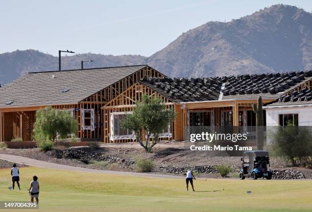 People golf by new homes under construction at a housing development near undeveloped Sonoran Desert on June 8, 2023 in Buckeye, Arizona. Buckeye is...