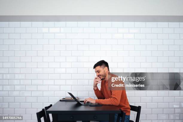 smiling businessman working on his laptop computer from the cafe - white computer keyboard stock pictures, royalty-free photos & images