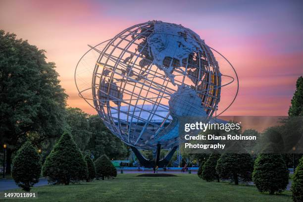 view of the unisphere, a spherical stainless steel representation of the earth in flushing meadows–corona park in the borough of queens in new york city at sunset - unisphere stock pictures, royalty-free photos & images