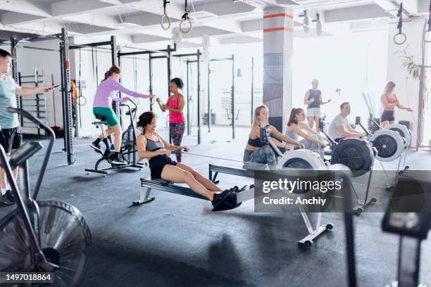 beautiful people working out in the gym with rowing machine - rowing machine stock pictures, royalty-free photos & images