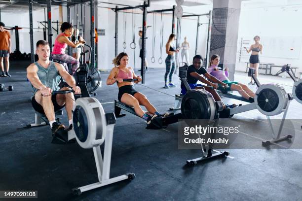 fit people working out in the gym with rowing machine - rowing machine stock pictures, royalty-free photos & images