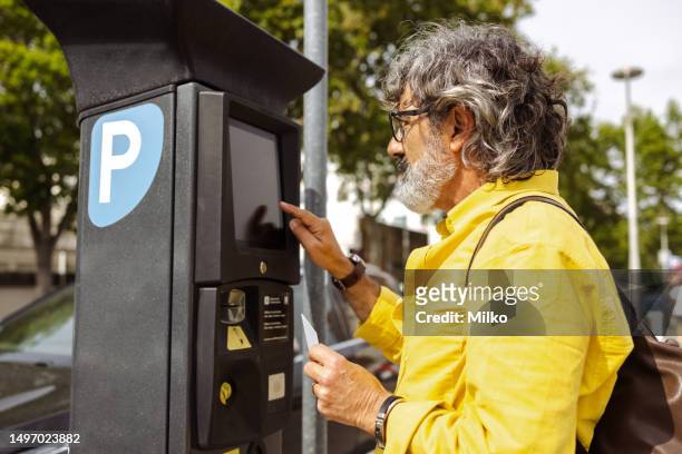 hombre mayor que usa la máquina de boletos de estacionamiento de pago - parking meter fotografías e imágenes de stock