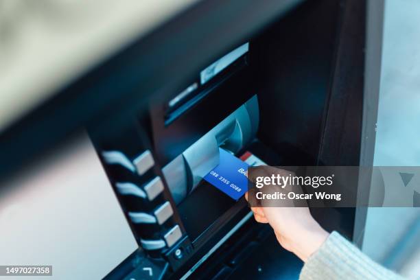 female hand inserting bank card into automatic cash machine to check account balance and withdraw cash from the automatic cash machine (atm) - high street bank uk stock pictures, royalty-free photos & images