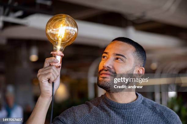 homme d’affaires créatif ayant une idée et tenant une ampoule - allumer photos et images de collection