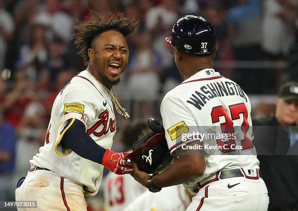 Ozzie Albies of the Atlanta Braves reacts as he hands his helmet to Ron Washington after hitting a three-run walk-off homer in the 10th inning...