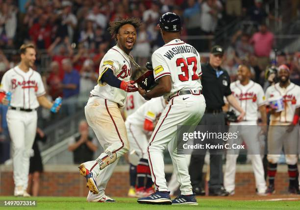 Ozzie Albies of the Atlanta Braves reacts as he hands his helmet to Ron Washington after hitting a three-run walk-off homer in the 10th inning...