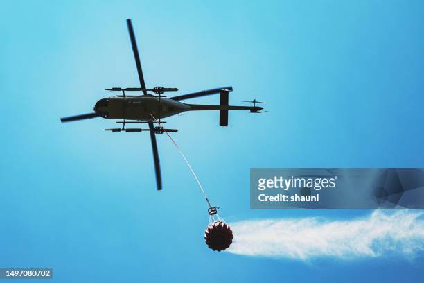 helicopter flies with water bucket - helicopter blades stock pictures, royalty-free photos & images