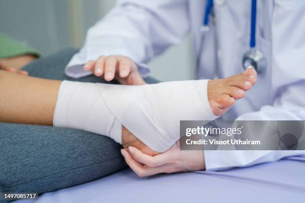 specialist helping troubled patient with foot injury,. - verstauchung stock-fotos und bilder