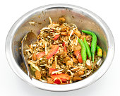 Burmese Tea Leaf Salad or Lahpet with green and red chilies in a steel dish.
