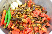 Burmese Tea Leaf Salad or Lahpet with green and red chilies, garlic in a steel dish.