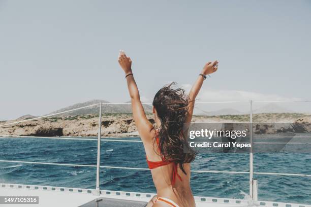 young latina woman enjoys a boat ride during holidays arms outstretched. - hair treatment stock pictures, royalty-free photos & images